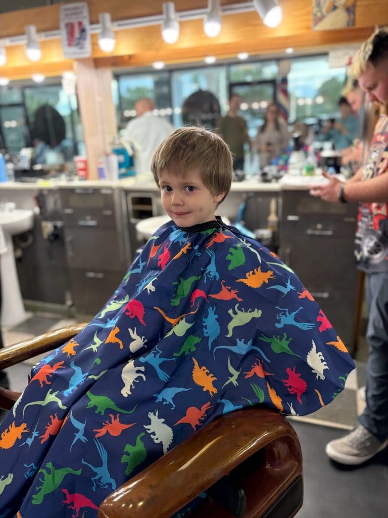 A young boy in a dinosaur cape before his haircut