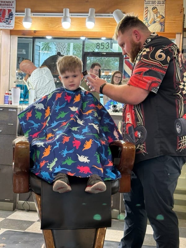 Kyle Wason cutting the boy's hair in the barber chair